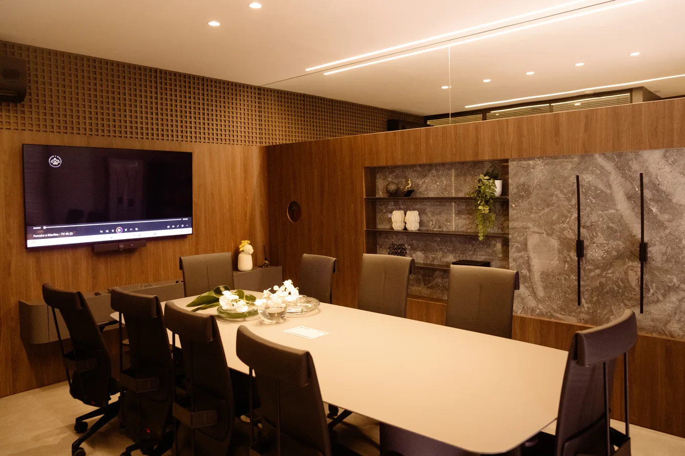 Sala de reunião com mesa longa e tela de apresentação